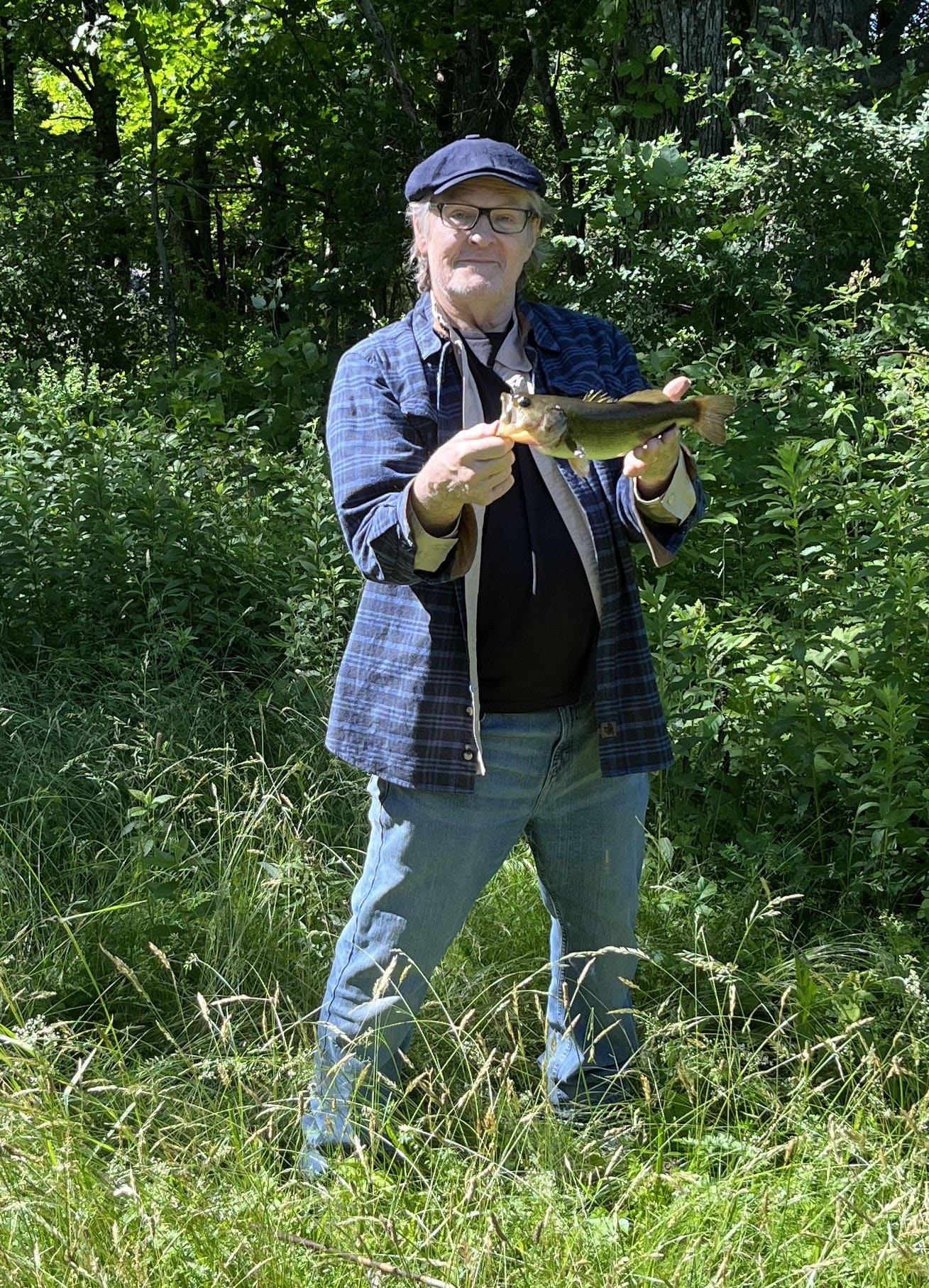 William Sadler, holding a fish he caught himself in the creek outside his home.